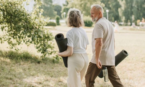 a man and woman walking with yoga mats